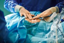 Обрізати невпізнаваного хірурга, який прикріплює клейку пов'язку на післяопераційному шві на грудях анонімного пацієнта після збільшення грудей — стокове фото