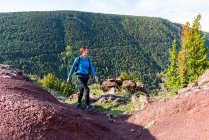 Wanderin mit Rucksack wandert an sonnigen Tagen in felsigem Gelände in den Bergen und schaut weg — Stockfoto
