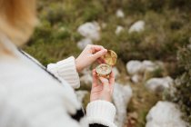 D'en haut de la culture touriste anonyme femelle en utilisant boussole sur la montagne avec des pierres rugueuses en plein jour — Photo de stock