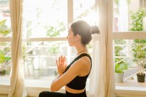 Junge, flexible, verträumte Frau in Sportbekleidung, die mit geschlossenen Augen auf einer Yogamatte im Haus Padmasana posiert — Stockfoto
