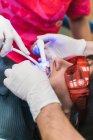 High angle crop anonymous dentist in gloves using dental ultraviolet curing light tool during procedure with patient in clinic — Stock Photo