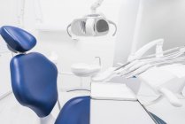 Інтер'єр охайної легкої стоматологічної клініки з синім стільцем і сучасним буровим апаратом — стокове фото