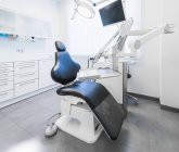 Інтер'єр охайної легкої стоматологічної клініки з синім стільцем і сучасним буровим апаратом — стокове фото