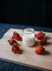 Von oben transparentes Glas Milch in der Nähe frischer süßer Erdbeeren für Smoothie auf schwarzem Hintergrund — Stockfoto