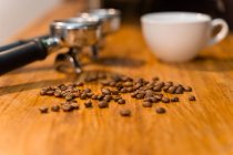 Portafilters colocados na mesa de madeira com xícara vazia e grãos de café frescos no café — Fotografia de Stock