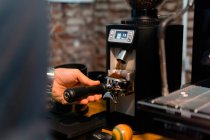 Растениеводство неузнаваемое бариста нажав кофе в портативном фильтре с вмешательством во время подготовки напитка в кафе — стоковое фото