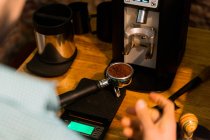 Растениеводство неузнаваемое бариста нажав кофе в портативном фильтре с вмешательством во время подготовки напитка в кафе — стоковое фото