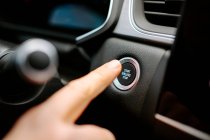 Closeup of crop anonymous male pressing Start Engine Stop button while sitting in modern car before driving — Stock Photo