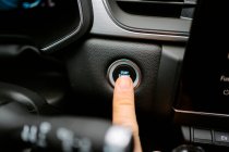 Closeup of crop anonymous male pressing Start Engine Stop button while sitting in modern car before driving — Stock Photo