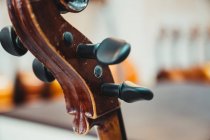 Pescoço de violino fino com cordas e pinos de afinação contra a parede branca no estúdio musical moderno — Fotografia de Stock