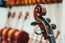 Pescoço de violino fino com cordas e pinos de afinação contra a parede branca no estúdio musical moderno — Fotografia de Stock