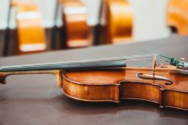 Modern shiny violin placed on shabby wooden table in workshop — Stock Photo