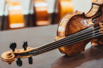 Moderne, glänzende Geige auf schäbigem Holztisch in Werkstatt platziert — Stockfoto