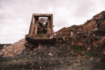 Шматок зруйнованої цементної будівлі на відкритій ямі з грубими каменями під хмарним небом в денне світло — стокове фото