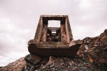 Pezzo di cemento distrutto su pozzo aperto con pietre grezze sotto cielo nuvoloso alla luce del giorno — Foto stock