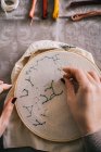 From above crop female with hoop and threads embroidering star constellations while sitting at table in light workshop — Stock Photo