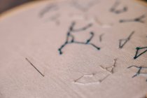 Stickereien von Sternenkonstellationen weben auf weißem Stoff im Reif mit scharfer Nadel — Stockfoto