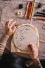 Top view crop female with hoop and threads embroidering star constellations while sitting at table in light workshop — Stock Photo