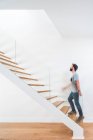 Side view of unrecognizable blurred male in casual outfit strolling on staircase near white wall and looking up in modern building — Stock Photo