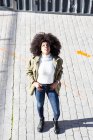 From above of expressive young black lady with Afro hairstyle in stylish clothes standing on paves street and smiling on sunny day — Stock Photo