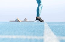 Ground level side view of runner standing on track near starting blocks and getting ready for race at stadium — Stock Photo
