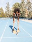 Знизу, під час тренувань, жінки - бігуни - афроамериканці стоять у позиції крохмалю, готуючись до спринту на стадіоні. — стокове фото
