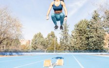 Визначений жіночий бігун стрибає над треком з стартових блоків під час підготовки до гонки на стадіоні під час тренування — стокове фото