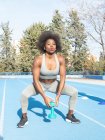 Athlète noire concentrée faisant des exercices avec haltère pendant l'entraînement au stade en été et impatiente — Photo de stock