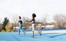 Fit multirassische Sportlerinnen reichen Stab beim Staffellauf entlang der Strecke im Stadion — Stockfoto