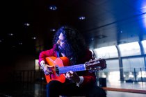 Male musician sitting on chair and playing guitar during rehearsal on stage — Stock Photo