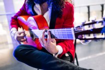 Урожай этнический человек с длинными волосами, играющий на акустической гитаре во время репетиции песни на сцене в свете внимания — стоковое фото