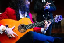 Ethnische männliche Musiker halten Akkord auf Saiten der Gitarre, während Musik mit Künstler bei einem Konzert — Stockfoto