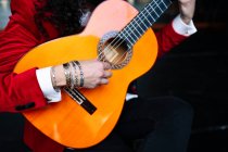 Музыкант, сидящий на стуле и играющий на гитаре во время репетиции на сцене — стоковое фото