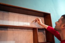 Seitenansicht männlich mit Pinsel Malerei Holzregale in weißer Farbe bei der Renovierung von Möbeln — Stockfoto