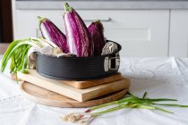 Fresh eggplants with green onions placed on table for cooking healthy vegetarian lunch at home — Stock Photo
