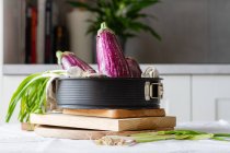 Fresh eggplants with green onions placed on table for cooking healthy vegetarian lunch at home — Stock Photo