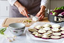Cultive cozinheiro irreconhecível preparando queijo para cozinhar aperitivos de berinjela com cebola verde em casa — Fotografia de Stock