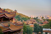 Authentic Buddhist temple located against modern multistory residential buildings in contemporary urban city in evening sun — Stock Photo