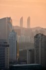 Мирный вид на современный мегаполис с небоскребами и жилыми зданиями под оранжевым небом в сумерках — стоковое фото