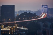 Zeitgenössische Hängebrücke in kreativem Design, die nachts die Straße in der modernen Stadt überquert — Stockfoto