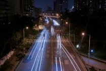 Longa exposição estrada de asfalto ocupado com veículos de condução na metrópole urbana contemporânea à noite — Fotografia de Stock