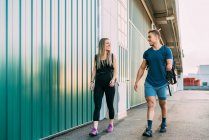 Young fit happy sportswoman and handicapped sportsman walking into gym together looking at each other — Stock Photo