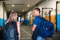 Back view of young fit happy sportswoman and handicapped sportsman walking into gym together — Stock Photo