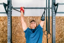 Young athlete handicapped sportsman training on horizontal bar during training in gym — Stock Photo