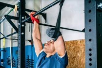 Jeune athlète sportif handicapé s'entraînant à la barre horizontale pendant l'entraînement en salle de gym — Photo de stock