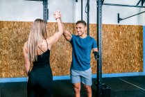 Cheerful athlete couple giving high five after helping handicapped sportsman on horizontal bar training in gym — Stock Photo