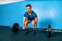 Poderoso atleta masculino sem mão levantando peso pesado durante o treinamento funcional perto de equipamentos esportivos no ginásio — Fotografia de Stock