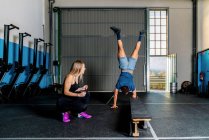 Junge lächelnde Sportlerin trainiert und hilft anonymen behinderten Sportlern beim Funktionstraining im Fitnessstudio — Stockfoto