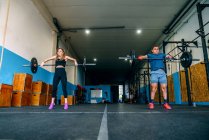 From below powerful sportswoman with handicapped male athlete lifting heavy weights and looking forward during functional training in gymnasium — Stock Photo