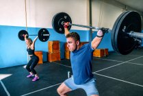 Kraftvolle Sportlerin mit behindertem Sportler beim Heben schwerer Gewichte und Vorfreude beim Functional Training in der Sporthalle — Stockfoto